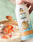 Bottle of Hazelnut Sugar Free Sinless Syrups held over a protein bowl with fruit and coconut.