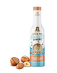 Bottle of sugar-free hazelnut coffee syrup with hazelnuts on a white background