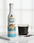 Sugar Free Madagascar Vanilla Sinless Syrup bottle with black coffee and vanilla bean on white background