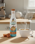 Sugar-free syrup bottle with a steaming cup of coffee on a kitchen counter