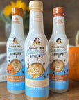 Three bottles of sugar-free coffee syrup with pumpkin and autumn decor on wood table