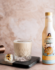 Toasted Marshmallow Sinless Syrup with a White Russian cocktail and marshmallows on a beige background