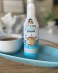 Sugar-free Madagascar Vanilla Sinless syrup bottle on a tray with a cup of coffee
