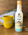 Sugar-free white chocolate coffee syrup with yellow mug and milk frother against blurred background