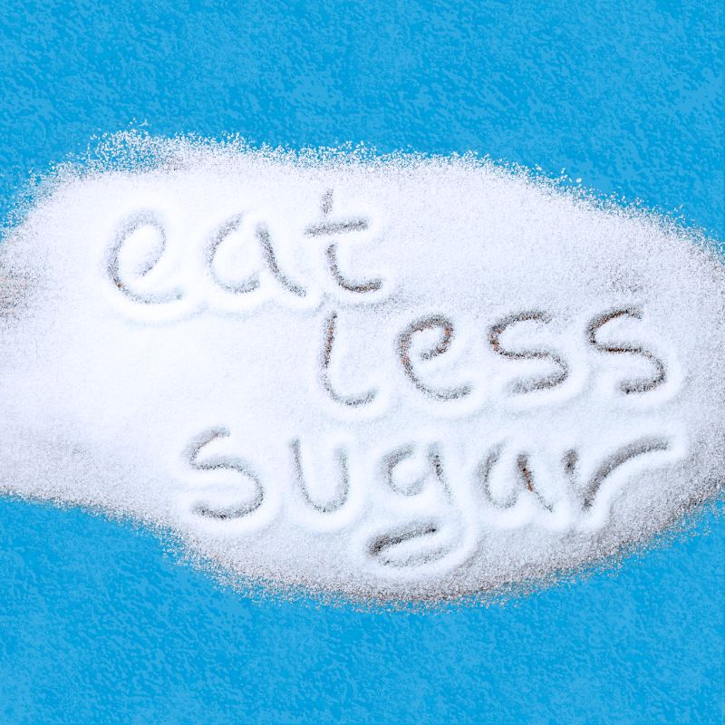 words "eat less sugar" written in sugar on blue background