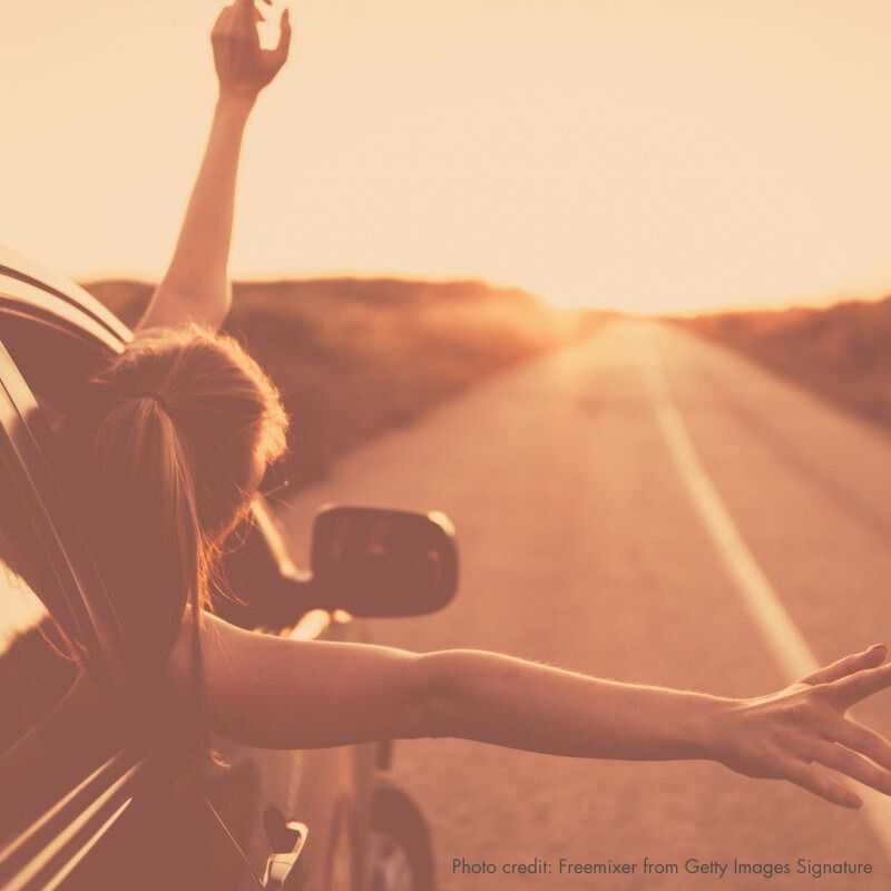 Woman leaning out car toward sunrise, photo credit: freemixer-GettyImagesSignature