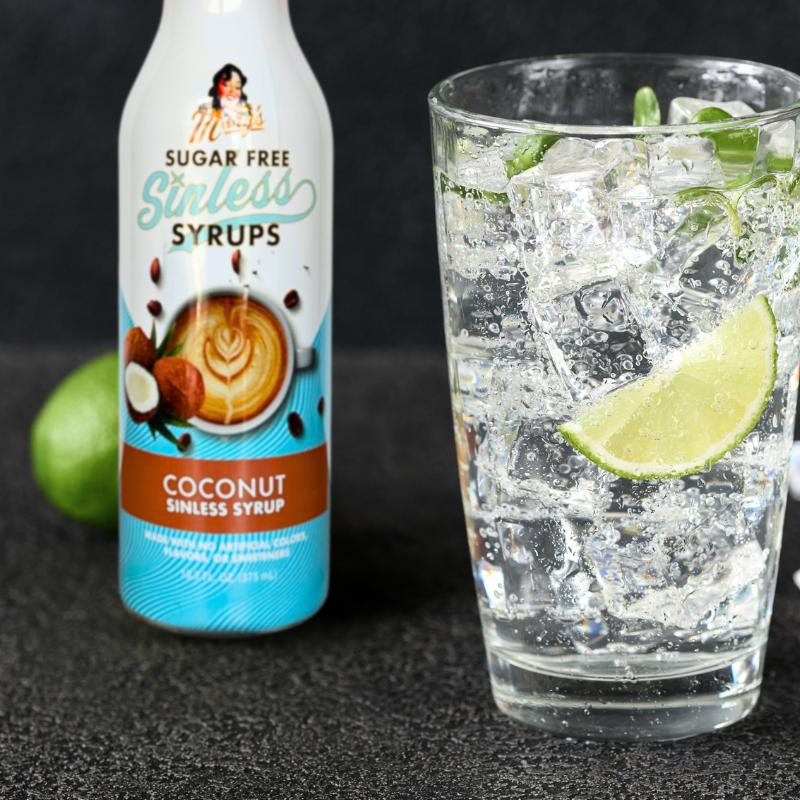 Coconut Sinless Syrup bottle and glass with lime on dark background