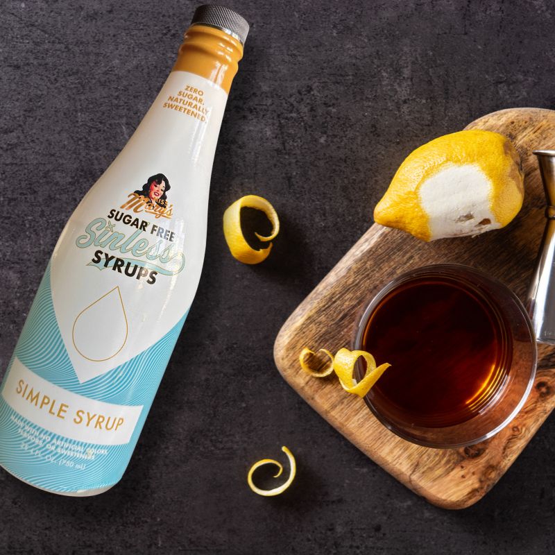 Sinless Simple Syrup bottle with sazerac cocktail and lemon peel on black background