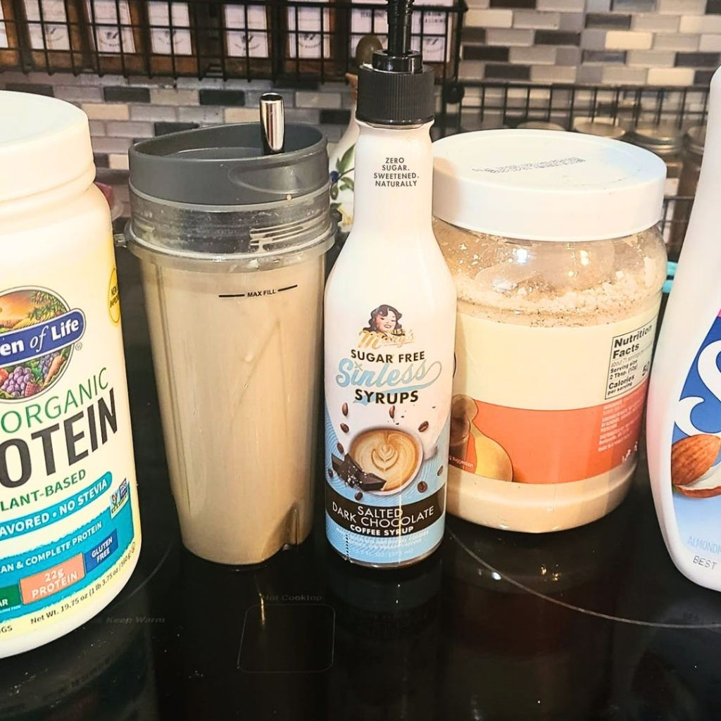 Salted Dark Chocolate Sinless Syrup and protein shake ingredients on obsidian counter