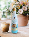 Bottle of Sugar Free Syrups on a table with a glass of iced coffee and flowers in the background