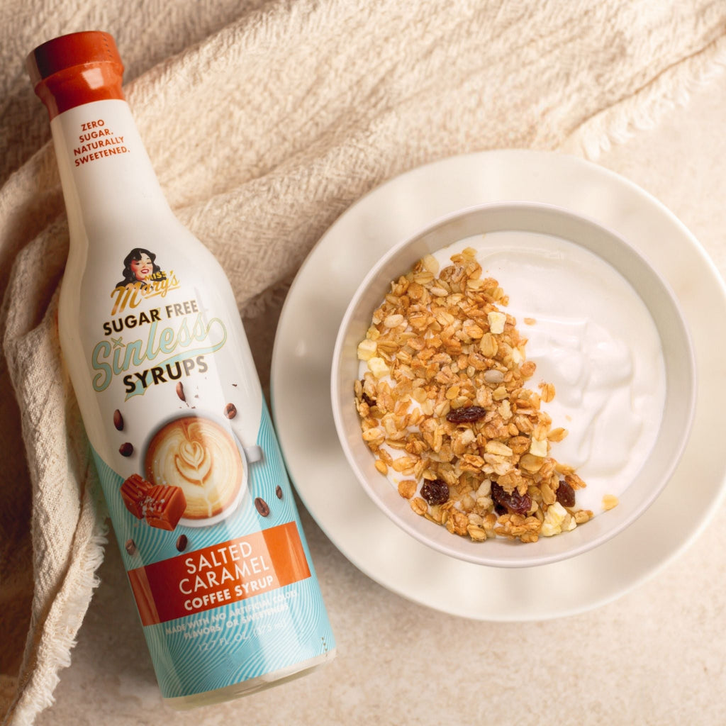 Miss Mary's Salted Caramel Sugar-Free coffee syrup and yogurt with granola on light brown table.