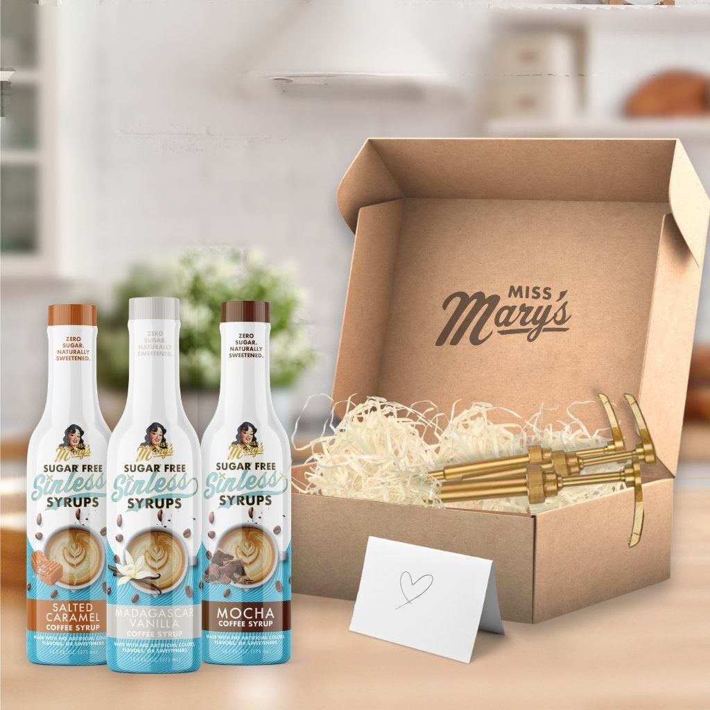 Three bottles of Miss Mary's sugar-free syrups in front of a cardboard box with the brand name.