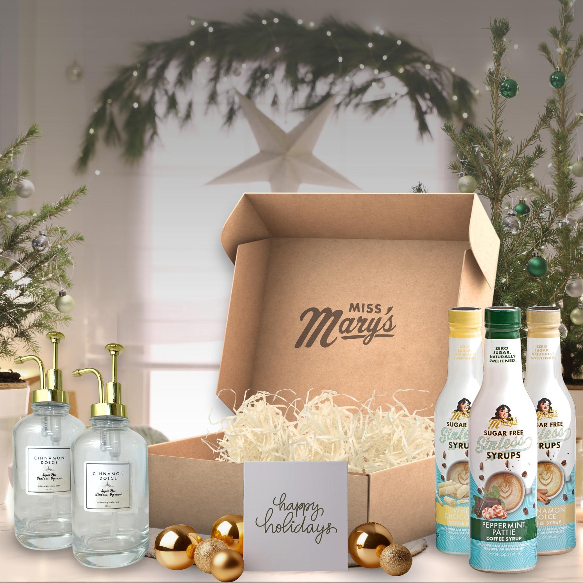 Gift box with 'Miss Mary's' branding, surrounded by decorative bottles and a Christmas tree.