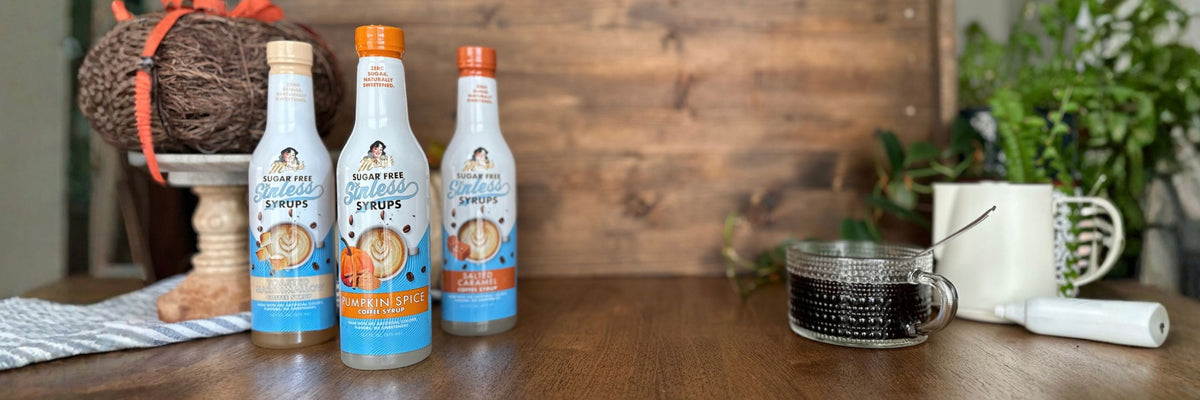 three coffee syrup bottles with pumpkin spice featured on wood table with coffee and autumn decor