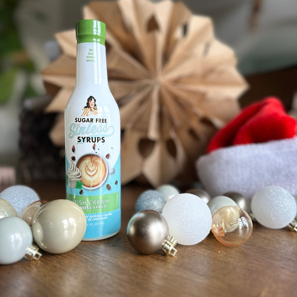 Irish Cream Sinless Syrup on a table decorated with Christmas ornaments and santa hat against blurred background