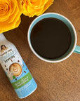Miss Mary's Irish Cream sugar-free coffee syrup against a wood table with a blue coffee mug and yellow roses