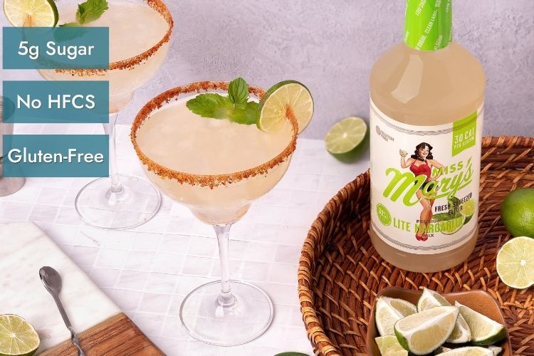 A bottle of Miss Mary's Lite Margarita with limes, a salted margarita glass, text overlays stating '5g Sugar', 'No HFCS', and 'Gluten-Free'.