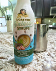 Peppermint Pattie Sinless Syrup with stainless steel pitcher on granite counter.