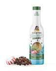 Bottle of sugar-free Peppermint Pattie Sinless Syrup and candies on white background