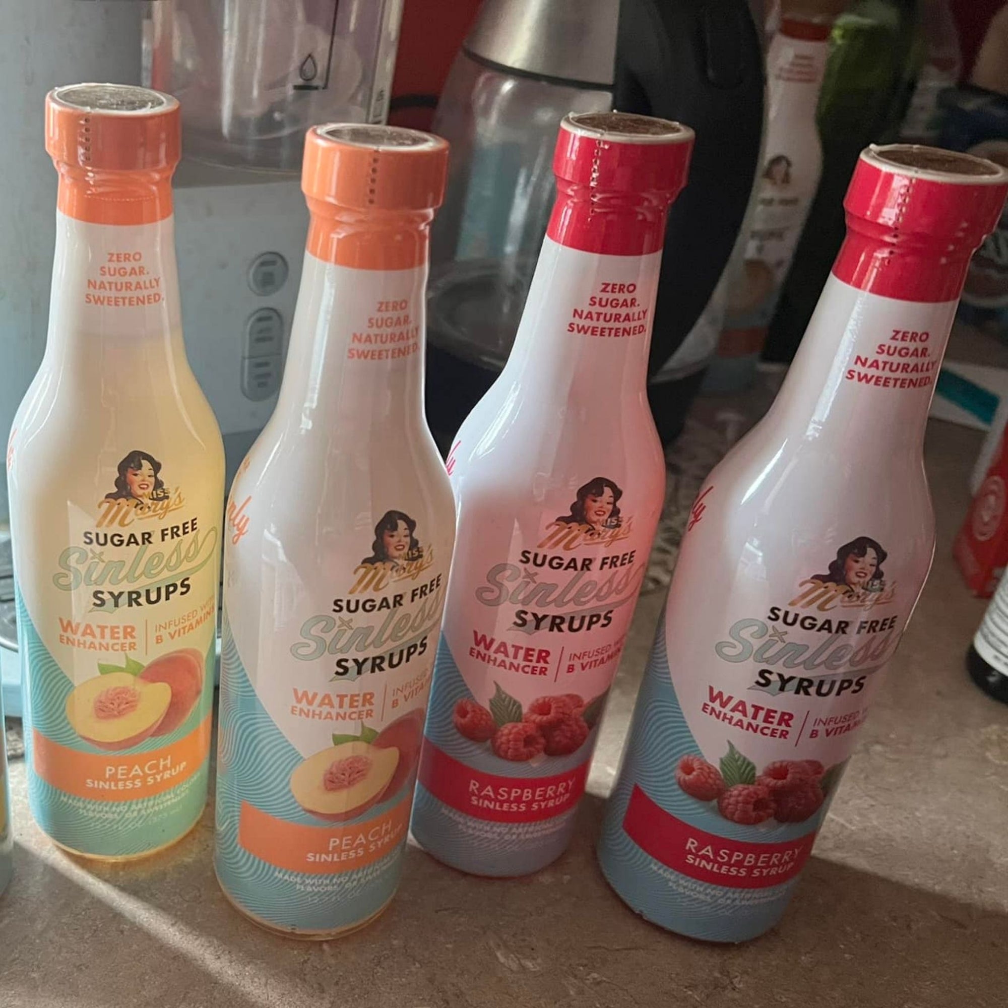 Four bottles of Fruit Sinless Syrups on a countertop with blurred background