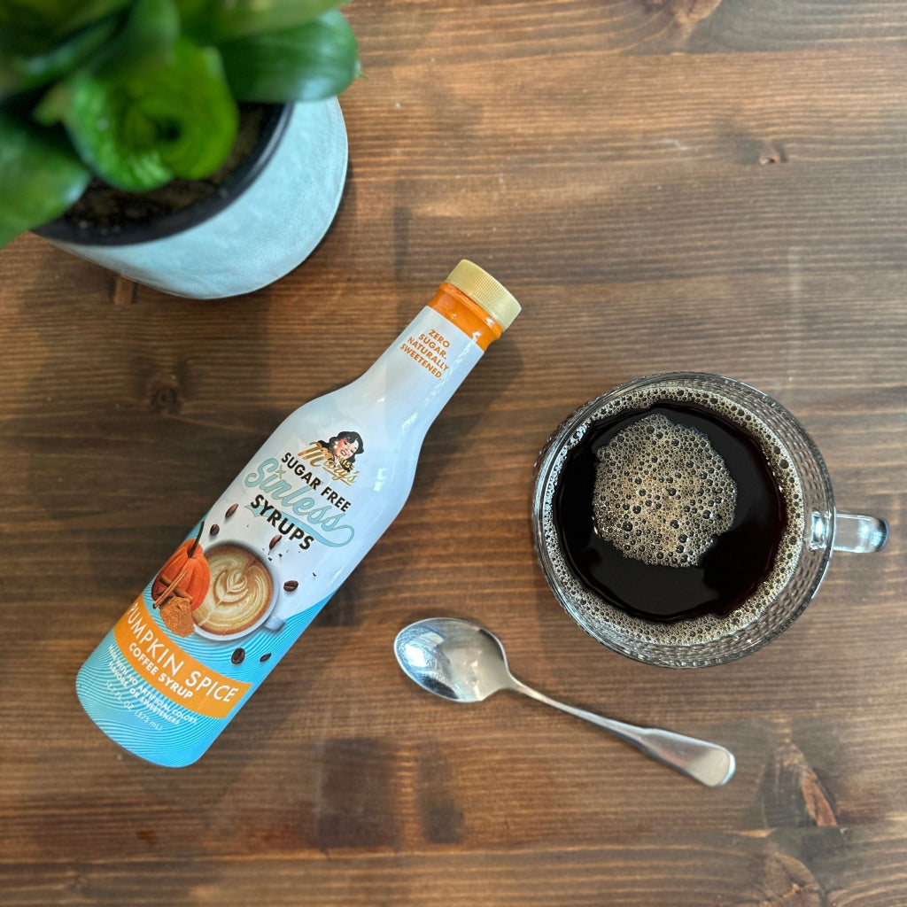 Pumpkin Spice Sugar-free Sinless Syrup on wood table with coffee, spoon, and plant