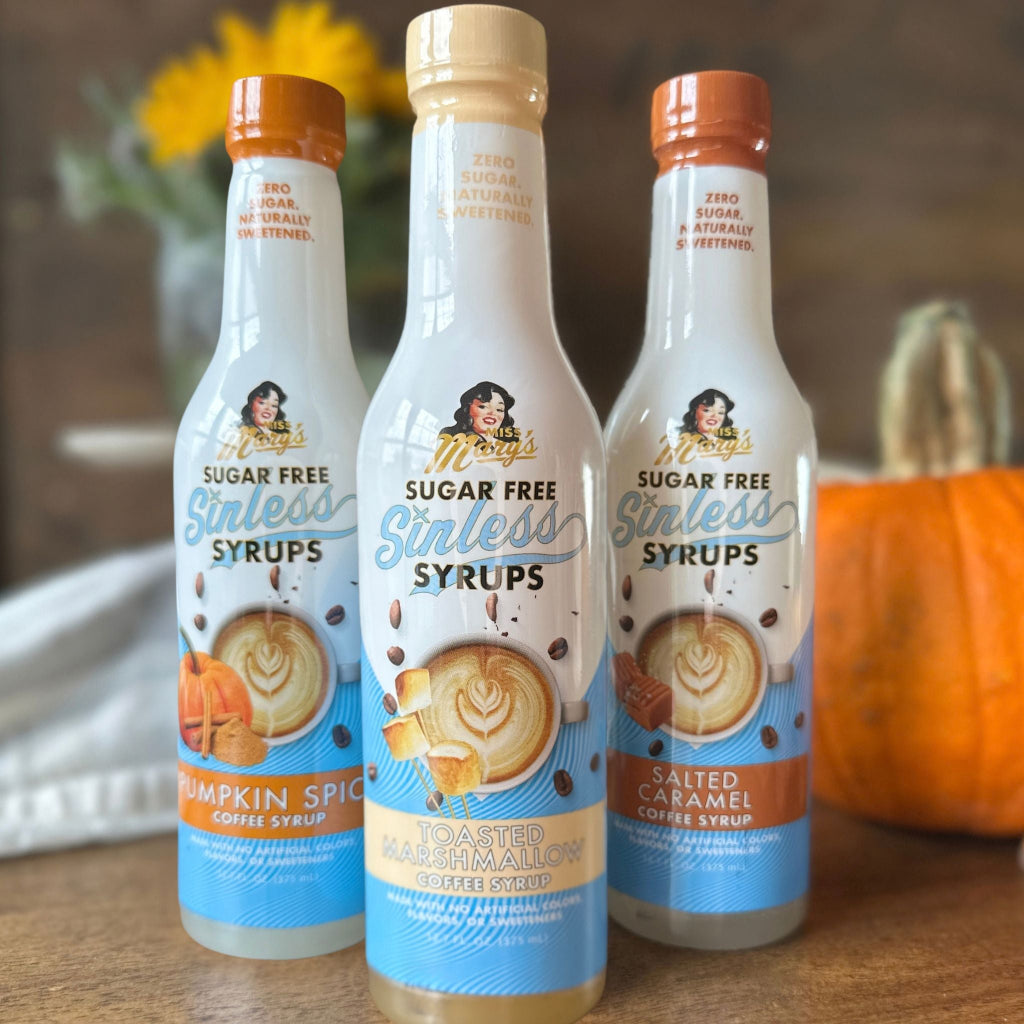 Three bottles  of sugar-free coffee syrup with pumpkin and autumn decor on wood table