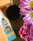 bottle of Toasted Marshmallow sugar-free Sinless Syrup on wood table with coffee and  pink flowers