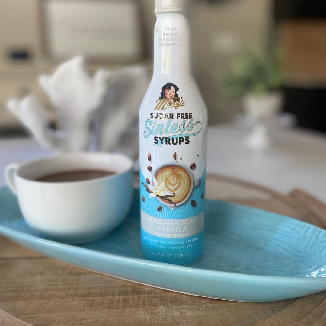 Sugar-free Madagascar Vanilla Sinless syrup bottle on a tray with a cup of coffee