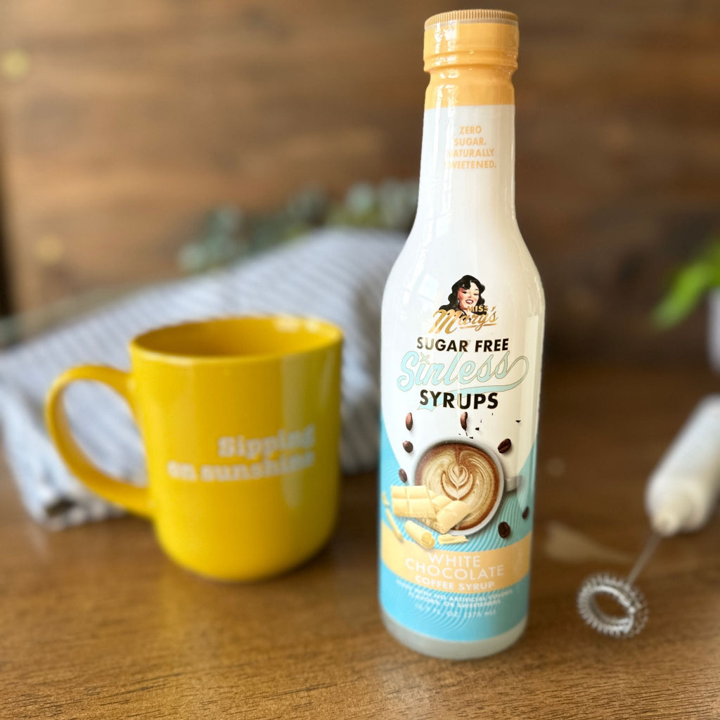 Sugar-free white chocolate coffee syrup with yellow mug and milk frother against blurred background